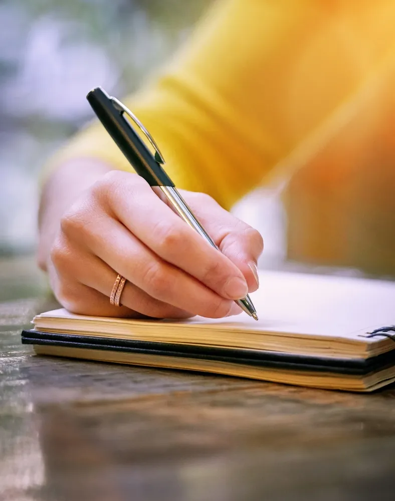 Author writing in a notebook with a pen